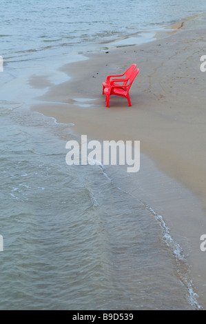 Rosso sedia in plastica sulla spiaggia in riva al Mar Mediterraneo di Tel Aviv in Israele Foto Stock