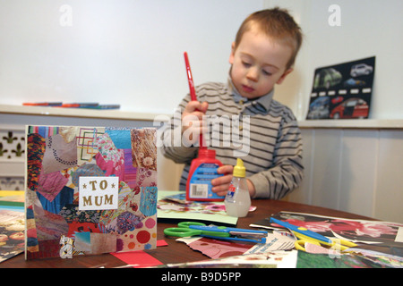 Un giovane bambino tagliare e incollare carta fatta a mano Foto Stock