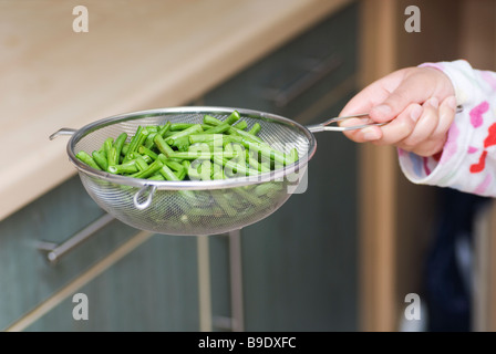 Mano che tiene un trito di fagioli verdi in un setaccio Foto Stock