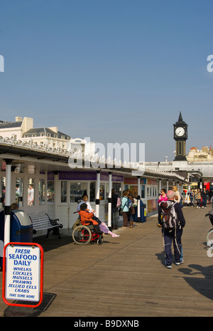 Una vista lungo il Palace Pier Brighton East Sussex England su una giornata di primavera con persone turisti Foto Stock