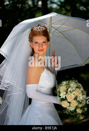 Mezzo corpo ritratto di sorridere sposa bouquet di contenimento sotto ombrellone Foto Stock