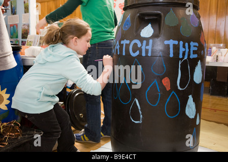 Bambini dipingere un barile di pioggia imparare circa la conservazione a una fiera verde a Syracuse, New York Foto Stock