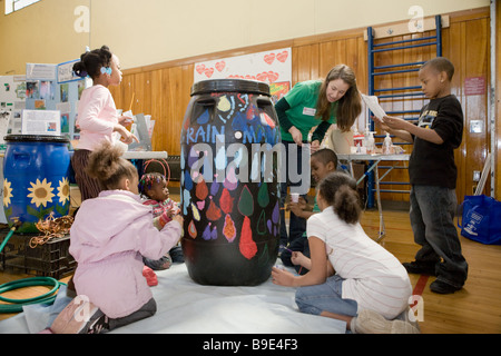 Bambini dipingere un barile di pioggia imparare circa la conservazione a una fiera verde a Syracuse, New York Foto Stock