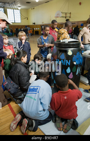 Bambini dipingere un barile di pioggia imparare circa la conservazione a una fiera verde a Syracuse, New York Foto Stock