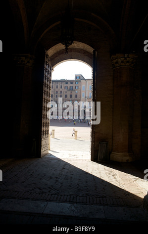 La porta aperta del La Torre del Mangia presi dall'interno con la luce del sole lo streaming attraverso la porta dalla Piazza del Campo a Siena Foto Stock