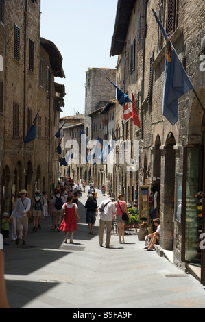 I turisti a piedi attraverso le antiche strade del pittoresco villaggio di San Gimignano in Toscana, Italia Foto Stock