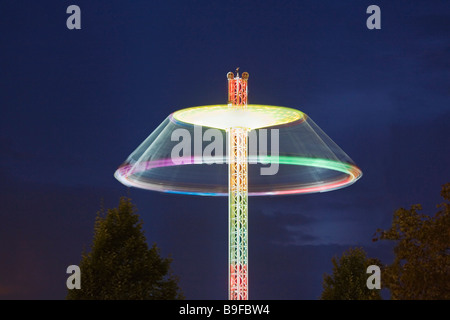 Illuminato di giostra in movimento al parco di divertimenti al crepuscolo Foto Stock