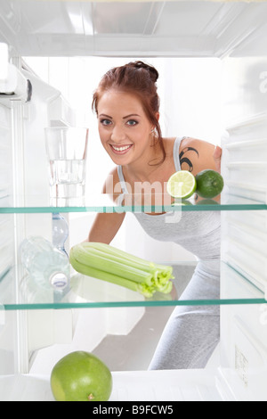 Ritratto di giovane donna sorridente nella parte anteriore del frigorifero aperto Foto Stock
