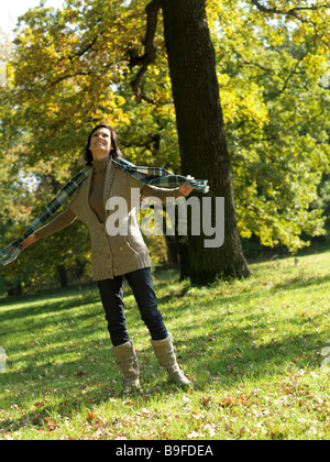 Donna matura in piedi nel parco e sorridente Foto Stock
