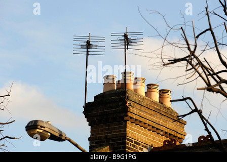 Una ciminiera in mattoni, comignoli e antenne in cima a una casa, piatta, maisonette nella città di Londra Foto Stock