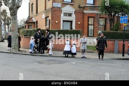 Scena di strada con ebrea ortodossa agli uomini e ai bambini in costume per la tradizionale festa di Purim,Stanford Hill, Londra Foto Stock