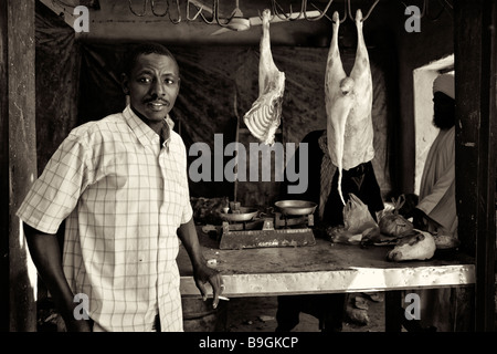 Uomo sudanese nella parte anteriore del negozio di macellaio, fumatori, nella città di debba, Sudan settentrionale, Africa Foto Stock