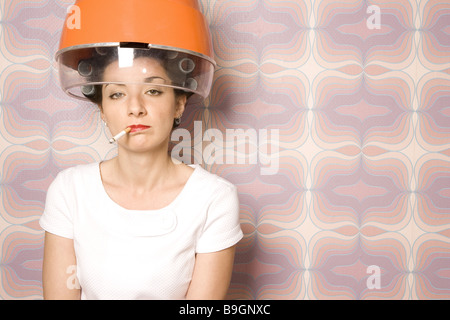 Salone di coiffeur donna bigodini essiccatore Fumi sigarette semi-portrait 20-30 anni 70er anni bellezza donna parrucchiere-visita Foto Stock
