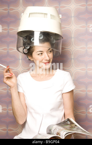 Salone di coiffeur donna bigodini essiccatore illustrato lettura Fumi sigarette semi-portrait 20-30 anni 70er anni prestige Foto Stock