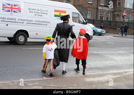 Un ebreo ortodosso uomo con due bambini vestiti in abiti fantasiosi costumi per la tradizionale festa di Purim,Stamford Hill Londra Foto Stock