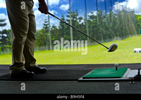 Un uomo di colpire palline da golf a una gamma di guida Foto Stock