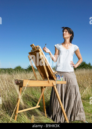 Donna pittura in un campo, sorridente Foto Stock