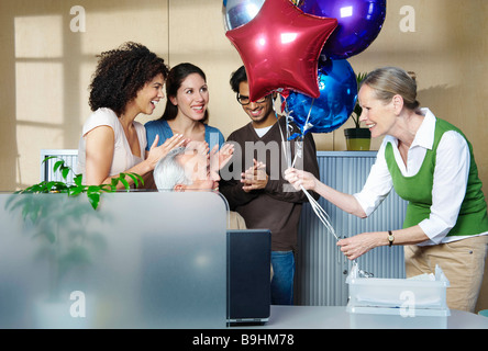 Gruppo di persone celebrando co-lavoratore Foto Stock