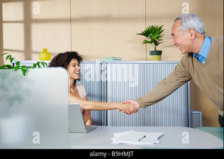 L uomo e la donna si stringono la mano al banco Foto Stock