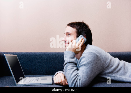 Uomo che stabilisce con il computer portatile sul lettino Foto Stock