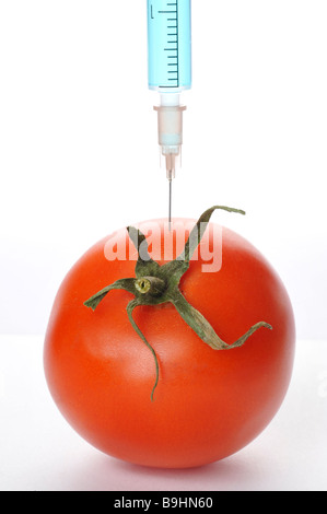 Siringa in un pomodoro, simbolico per organismi geneticamente manipolati alimenti Foto Stock