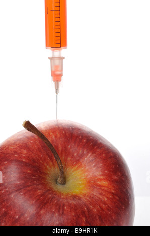 Ago di iniezione in un apple, immagine simbolica per gli alimenti geneticamente modificati Foto Stock