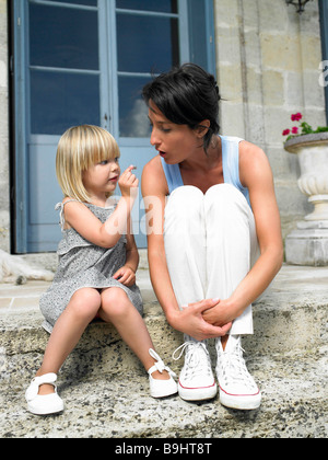 Madre e figlia sul gradino della porta Foto Stock