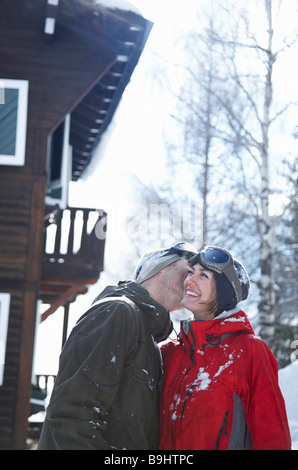 Coppia giovane di fronte chalet kissing Foto Stock