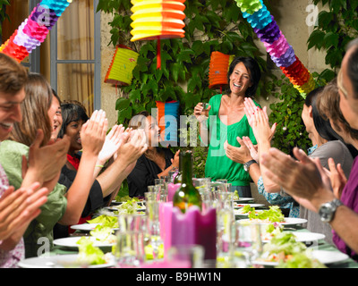 La gente seduta a tavola, celebrando Foto Stock