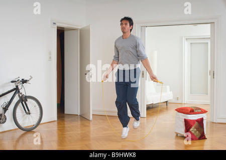 Uomo che salta con una corda in un appartamento Foto Stock