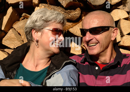 Il vecchio in età matura rilassarsi di fronte ad una pila di legno Foto Stock