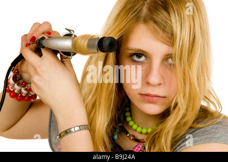 13-anno-vecchia ragazza arricciare i capelli con un ferro arricciacapelli Foto Stock