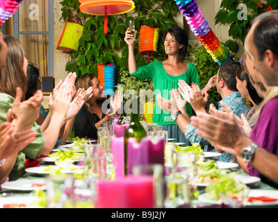 La gente seduta a tavola, celebrando Foto Stock