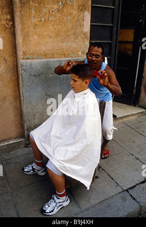 Parrucchiere cubano il taglio di un ragazzo in capelli sulla strada, La Habana Vieja, Havana, Cuba, Caraibi Foto Stock