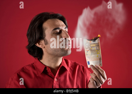 Uomo con un ardente 50-Euro bill Foto Stock