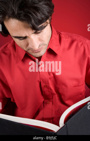 Uomo che indossa una maglietta rossa in possesso di un libro Foto Stock