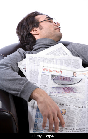 Giovane uomo di dormire su una poltrona in pelle con un giornale Foto Stock