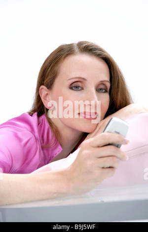 Donna che indossa una camicetta rosa, tenendo il suo mobile Foto Stock