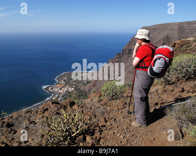 Donna con uno zaino, godendo la vista dal Monte Las Pilas, La Playa in Valle Gran Rey, La Gomera, isole Canarie, Spagna, Europa Foto Stock