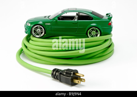 Un verde automobile automobile su un verde avvolto a spirale prolunga elettrica cavo di alimentazione con una spina Foto Stock