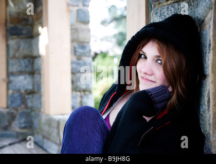 Giovane femmina caucasica appoggiata sulla parete di pietra Foto Stock