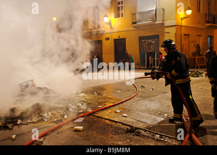 Fireman radioestesia le fiamme di un ardente Ninot scultura La Crema durante il culmine del festival Las Fallas a Valencia Spagna Foto Stock