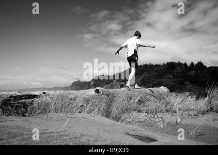 Un uomo saldi su un registro vicino alla spiaggia di Redwoods National Park, California. Foto Stock