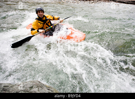 Un playboater gode di una piccola onda sulle rive di un fiume. Foto Stock