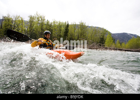 Un playboater gode di una piccola onda sulle rive di un fiume. Foto Stock