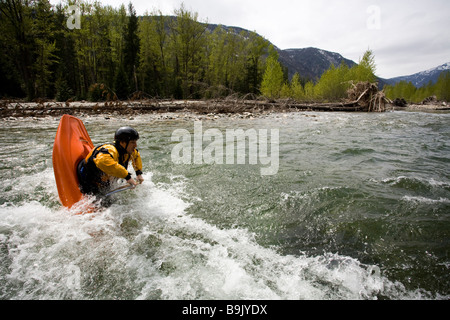 Un playboater gode di una piccola onda sulle rive di un fiume. Foto Stock