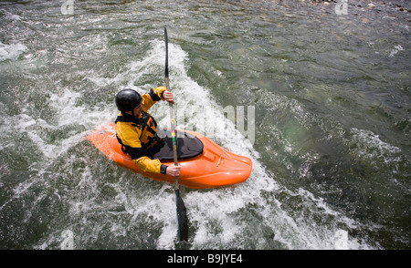 Un playboater gode di una piccola onda sulle rive di un fiume. Foto Stock