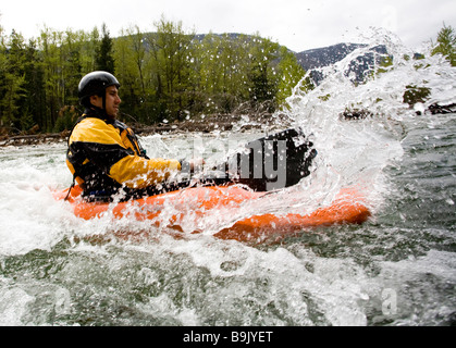 Un playboater gode di una piccola onda sulle rive di un fiume. Foto Stock