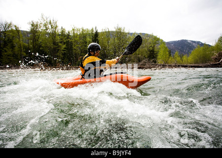 Un playboater gode di una piccola onda sulle rive di un fiume. Foto Stock