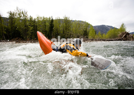 Un playboater gode di una piccola onda sulle rive di un fiume. Foto Stock